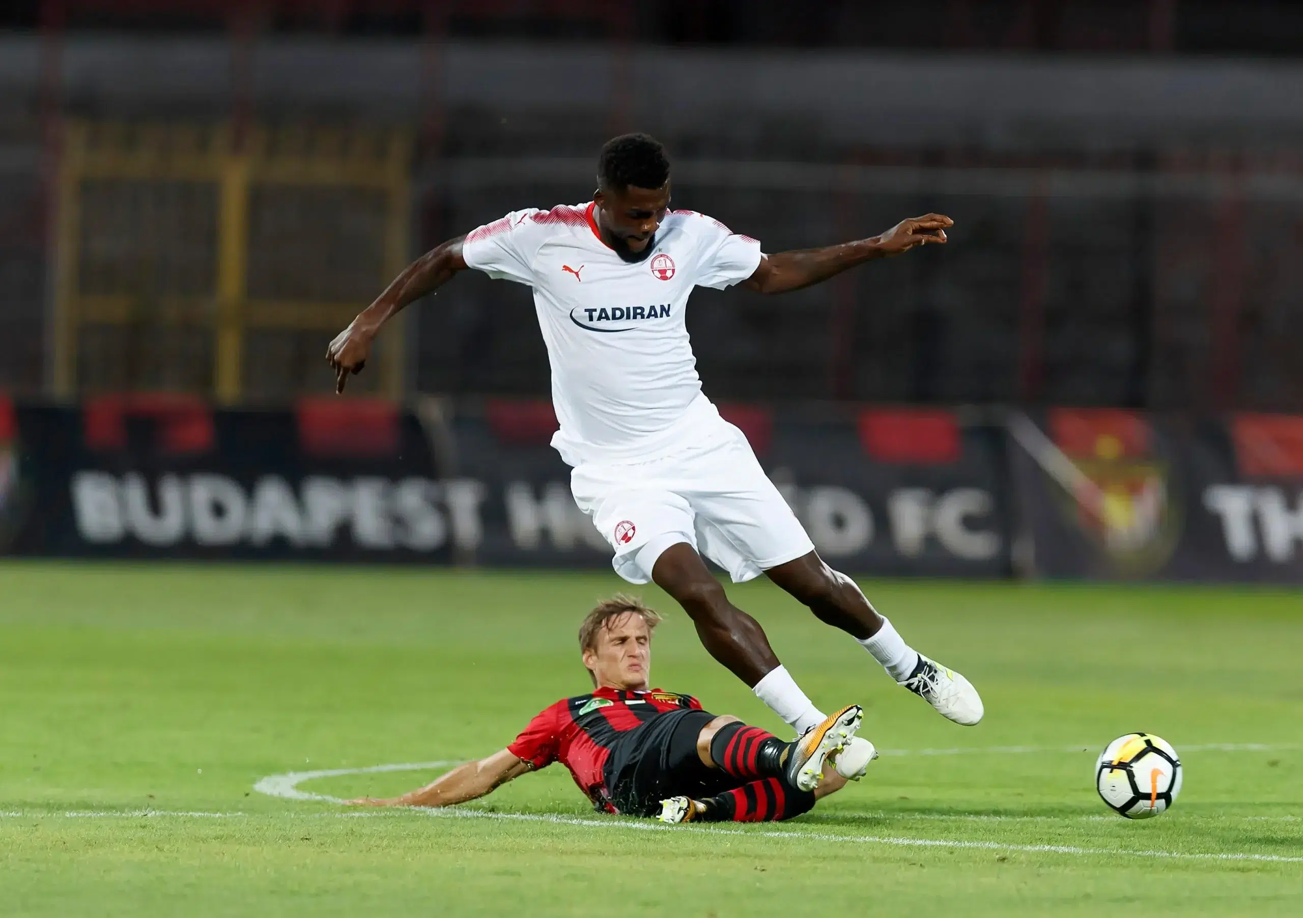 Gergo Nagy (L) of Budapest Honved slide tackles John Ogu (R) of Hapoel Beer-Sheva during the UEFA Champions League Second Qualifying Round match